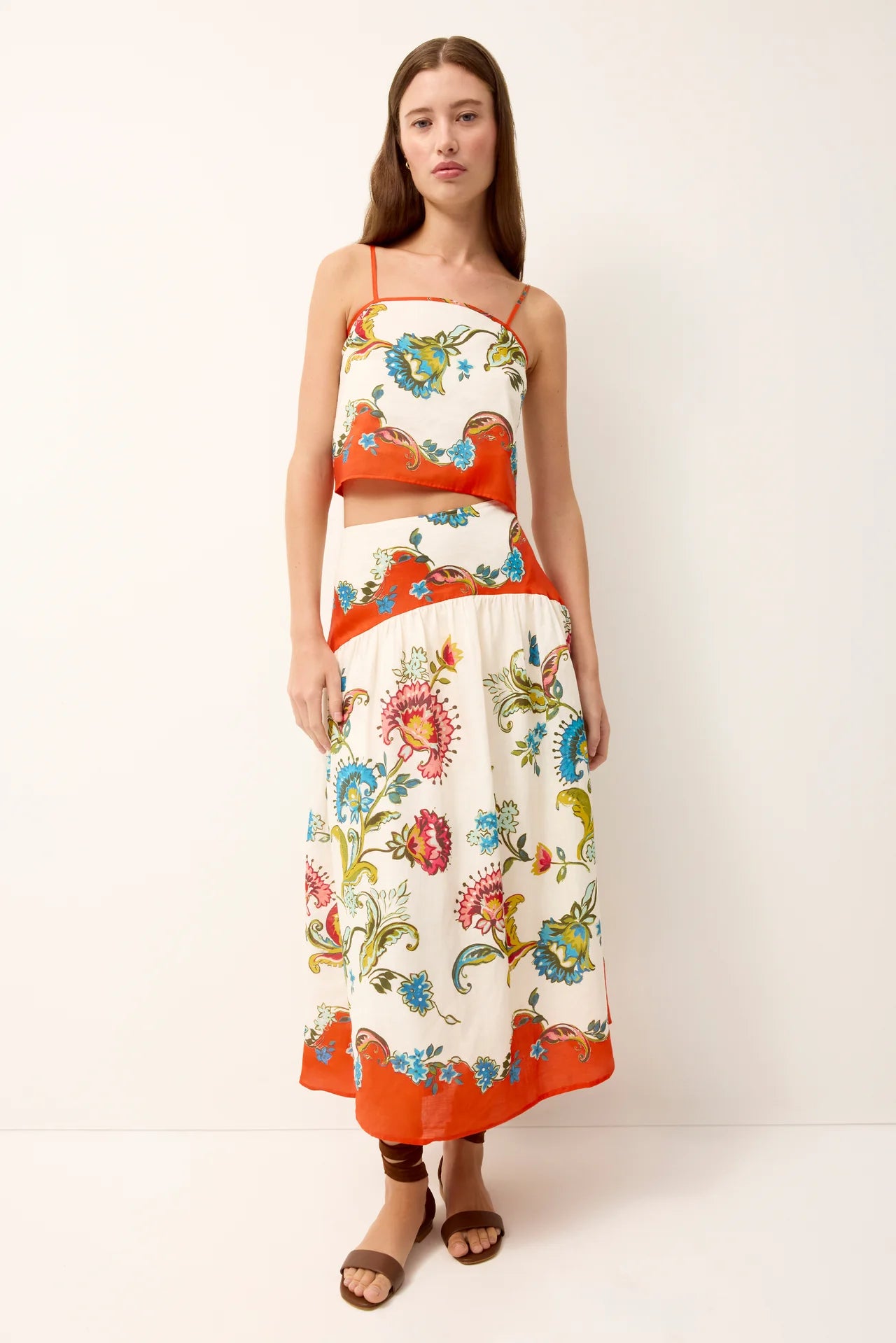 Woman wearing a colorful floral dress with an orange trim on a white background