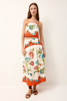 Woman wearing a colorful floral dress with an orange trim on a white background