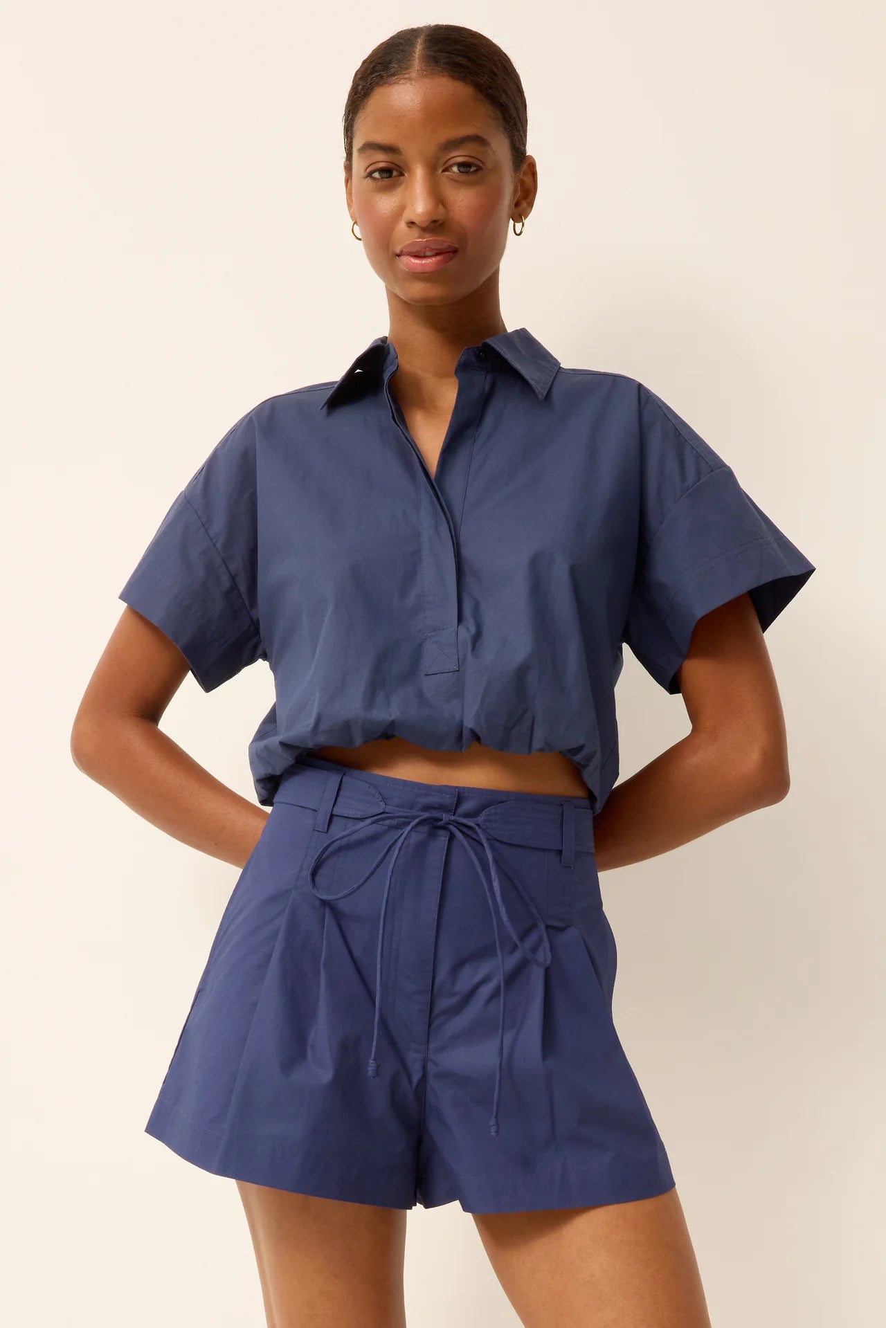 Woman wearing a blue outfit with a matching shirt and shorts on a plain background