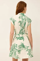 Woman wearing a white dress with green leaf pattern on a beige background