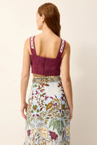 Woman wearing a maroon top and floral skirt on a beige background