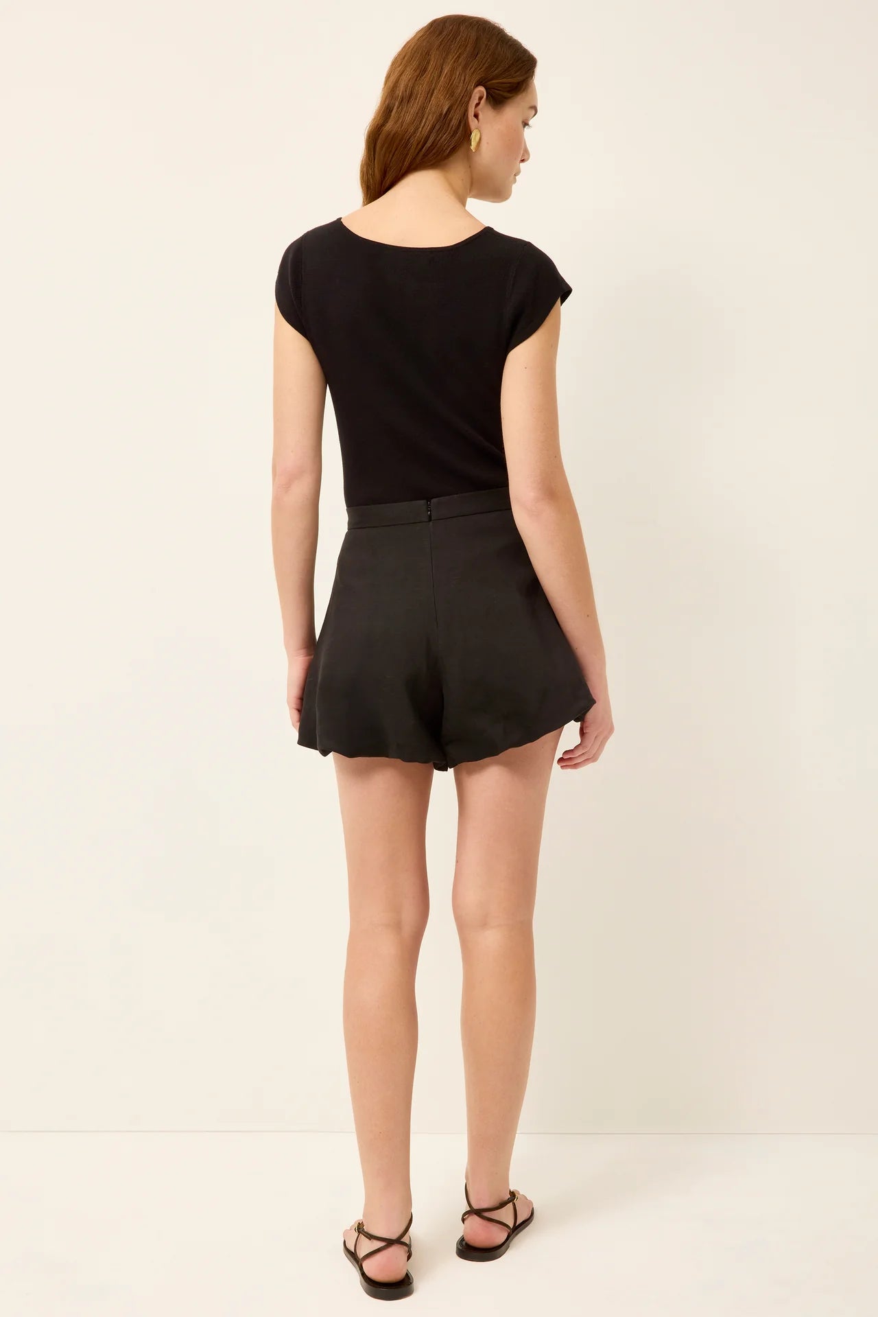 Woman wearing a black top and shorts on a white background
