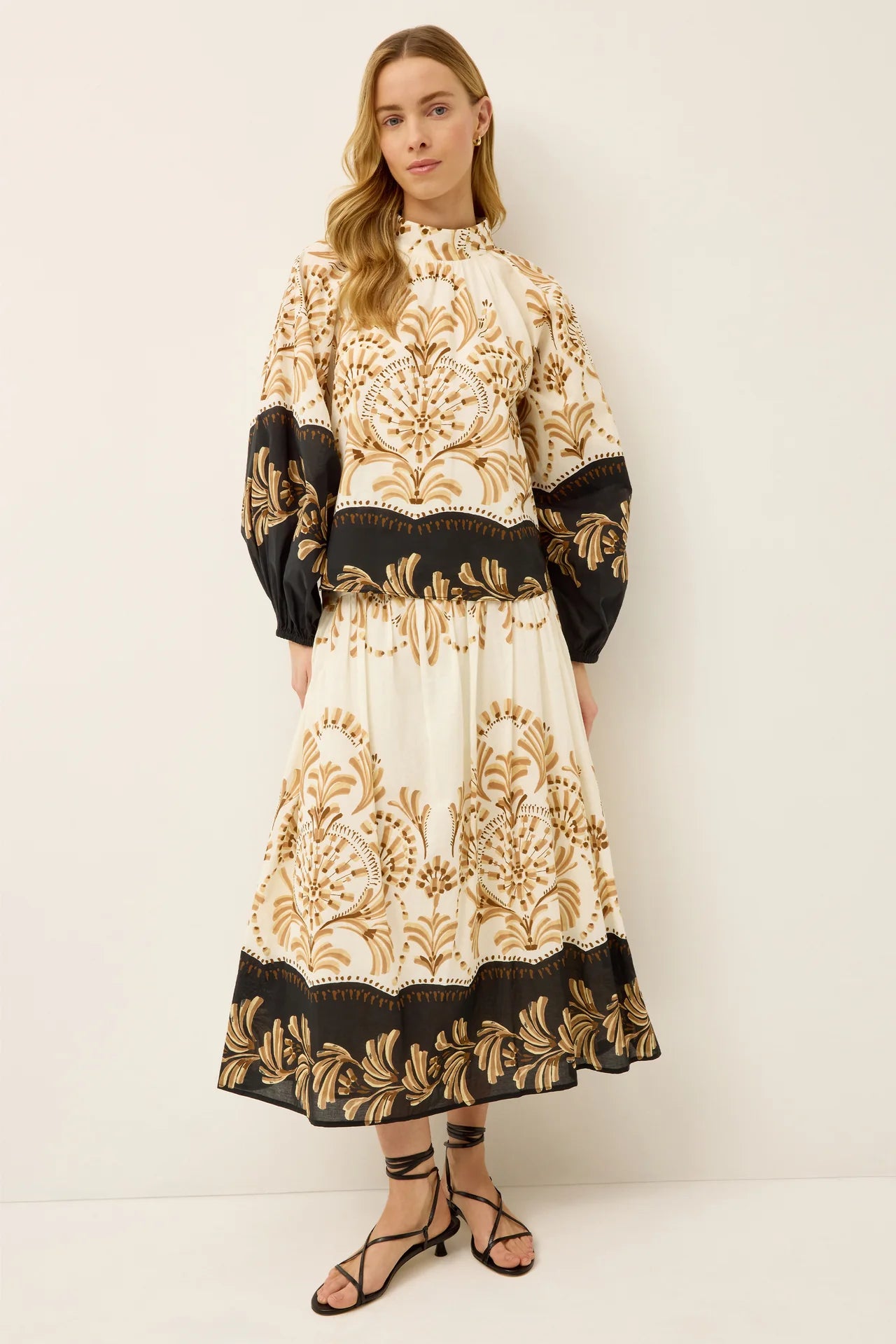 Woman wearing a black and gold patterned outfit on a white background