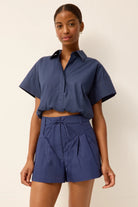 Woman wearing a blue outfit with a matching shirt and shorts on a beige background