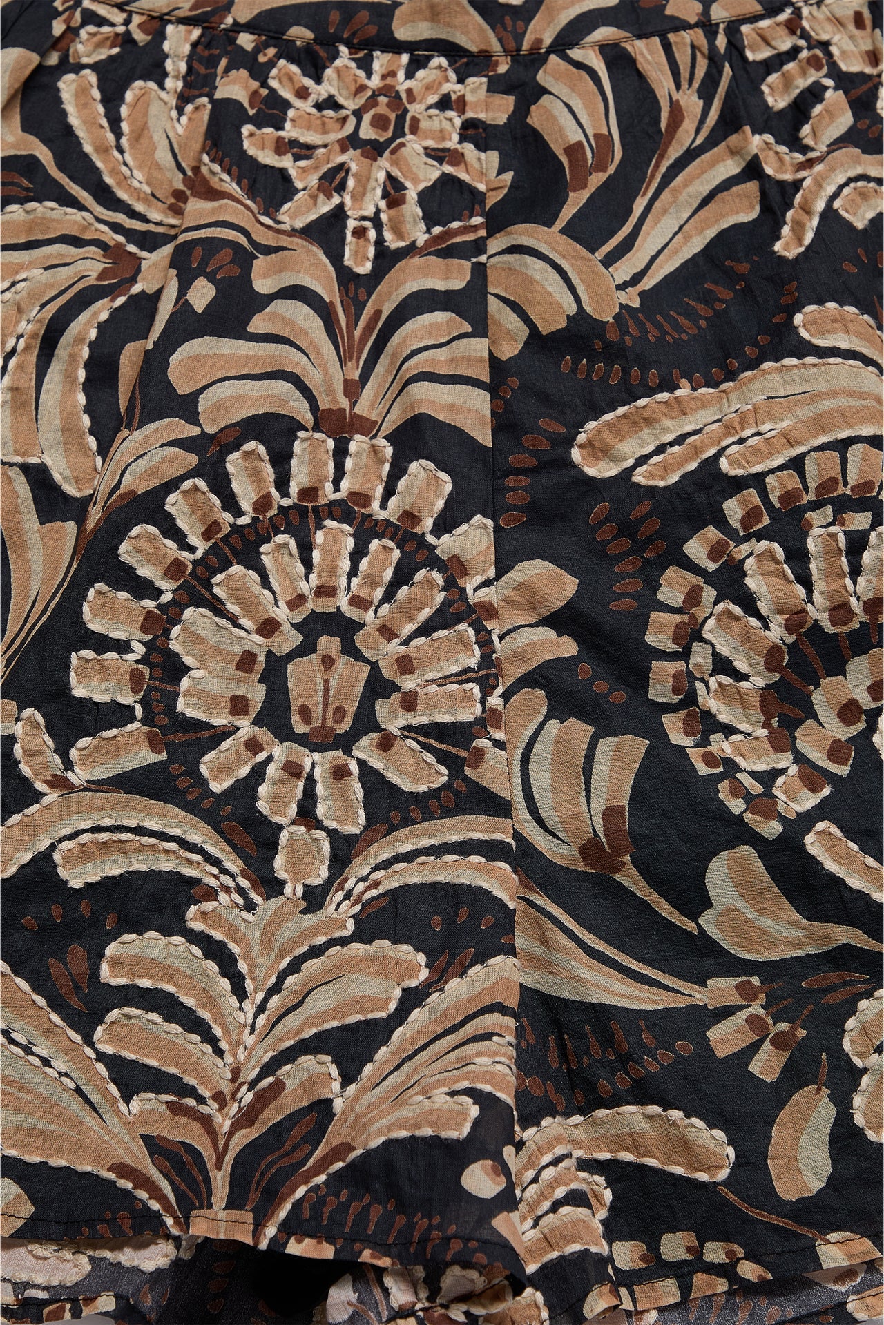 Close-up of a patterned fabric with brown and beige design on a dark background