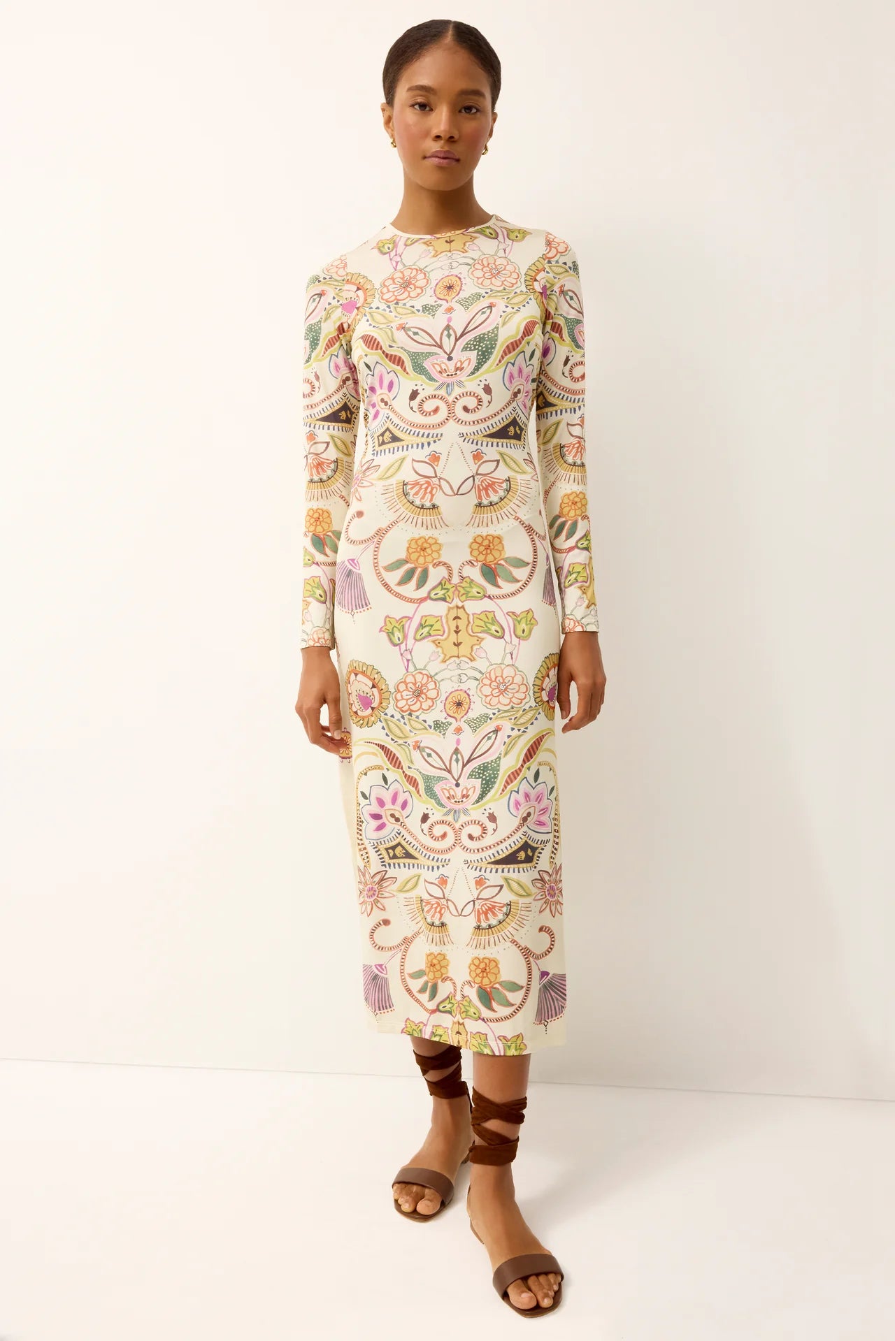 Woman wearing a long-sleeve, knee-length dress with floral patterns on a white background