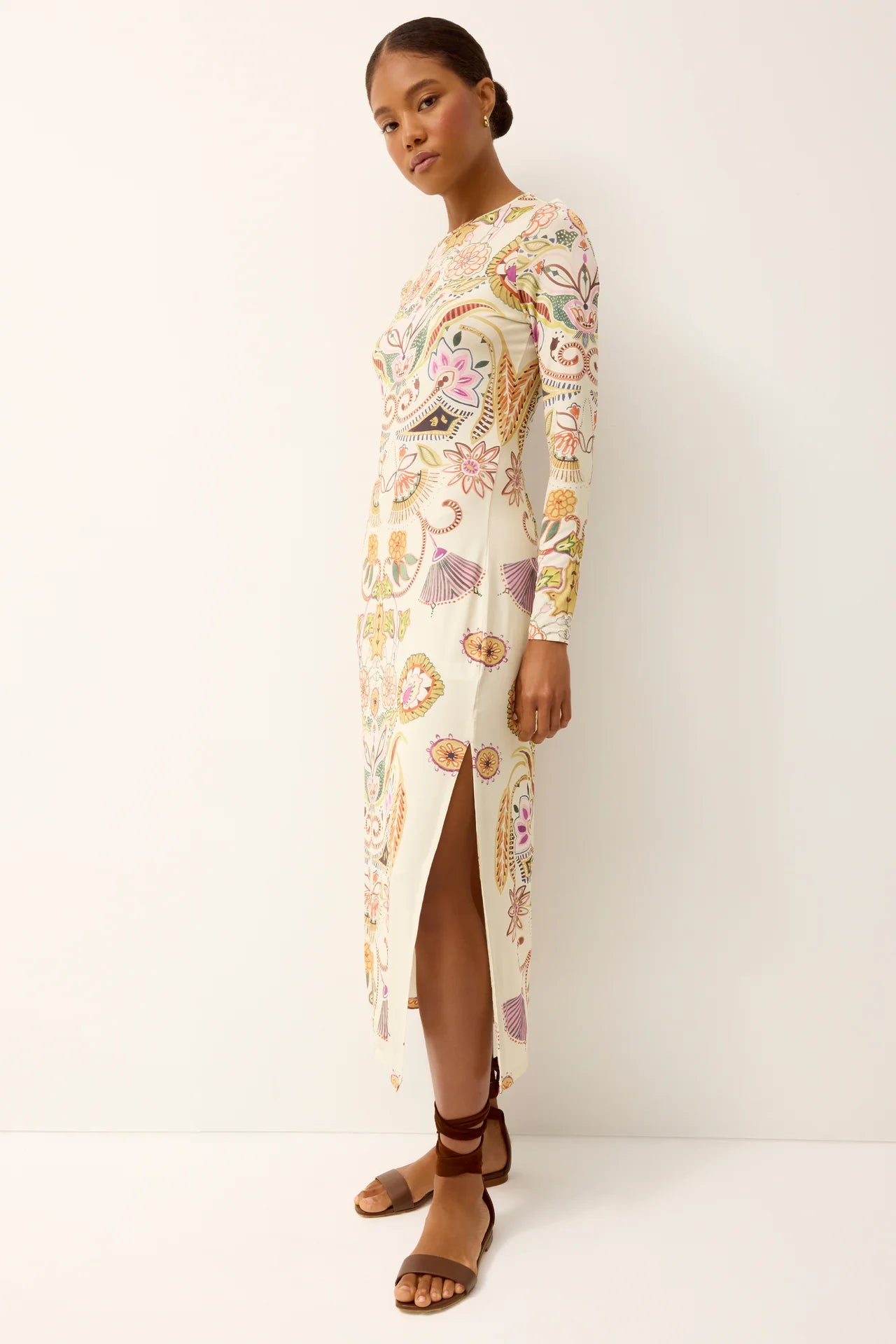 Woman wearing a long, floral-patterned dress against a white background