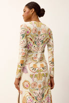 Woman wearing a long-sleeve dress with a colorful floral pattern on a white background