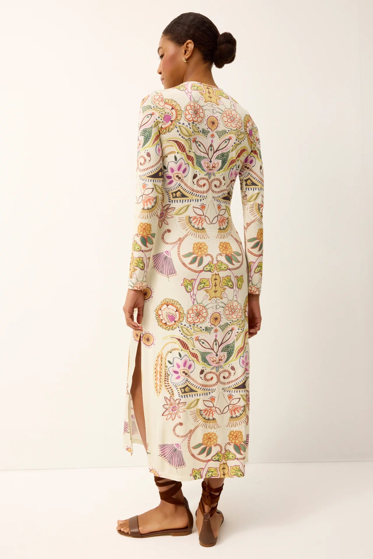 Woman wearing a long, floral embroidered dress on a white background