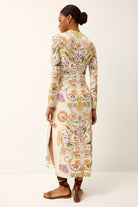 Woman wearing a long, floral embroidered dress on a white background