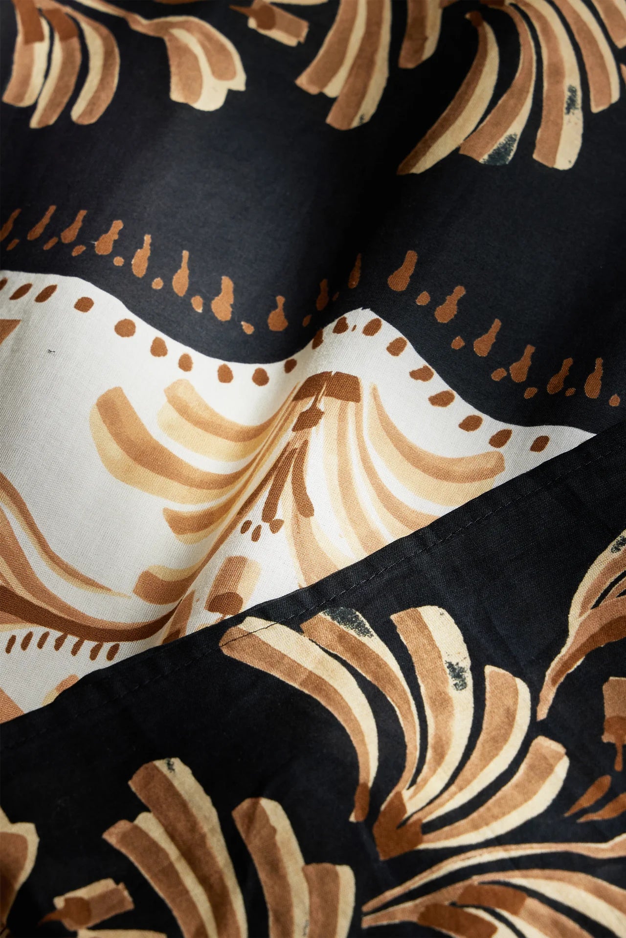 Close-up of a fabric with brown and beige floral patterns on a black background