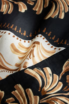 Close-up of a fabric with brown and beige floral patterns on a black background