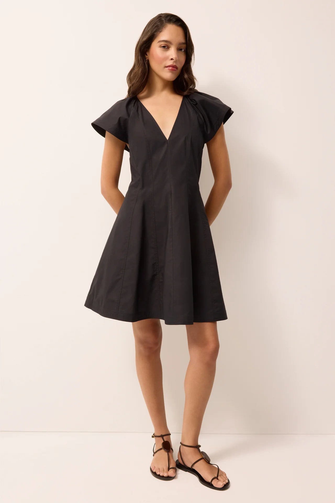 Woman wearing a black dress with ruffled shoulders on a white background