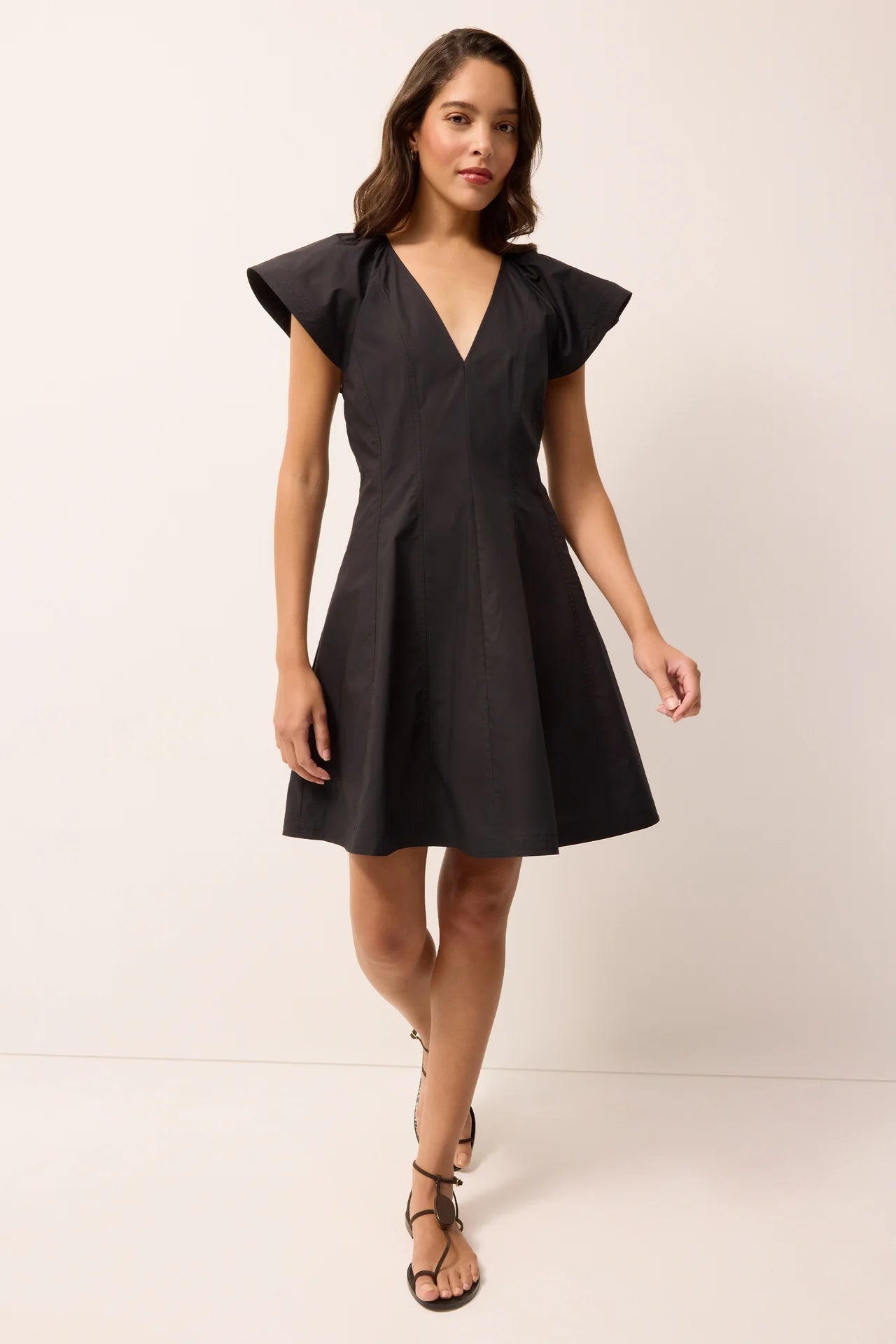 Woman wearing a black dress with ruffled shoulders on a white background