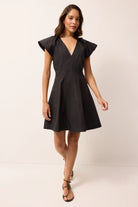 Woman wearing a black dress with ruffled shoulders on a white background