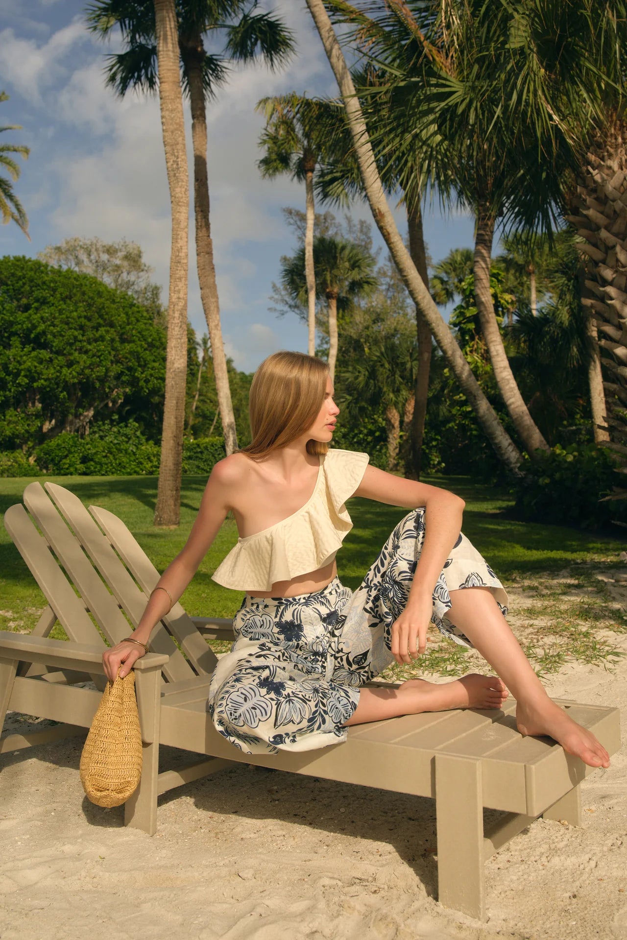 Woman sitting on a beach chair with palm trees in the background