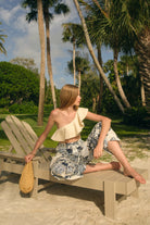 Woman sitting on a beach chair with palm trees in the background