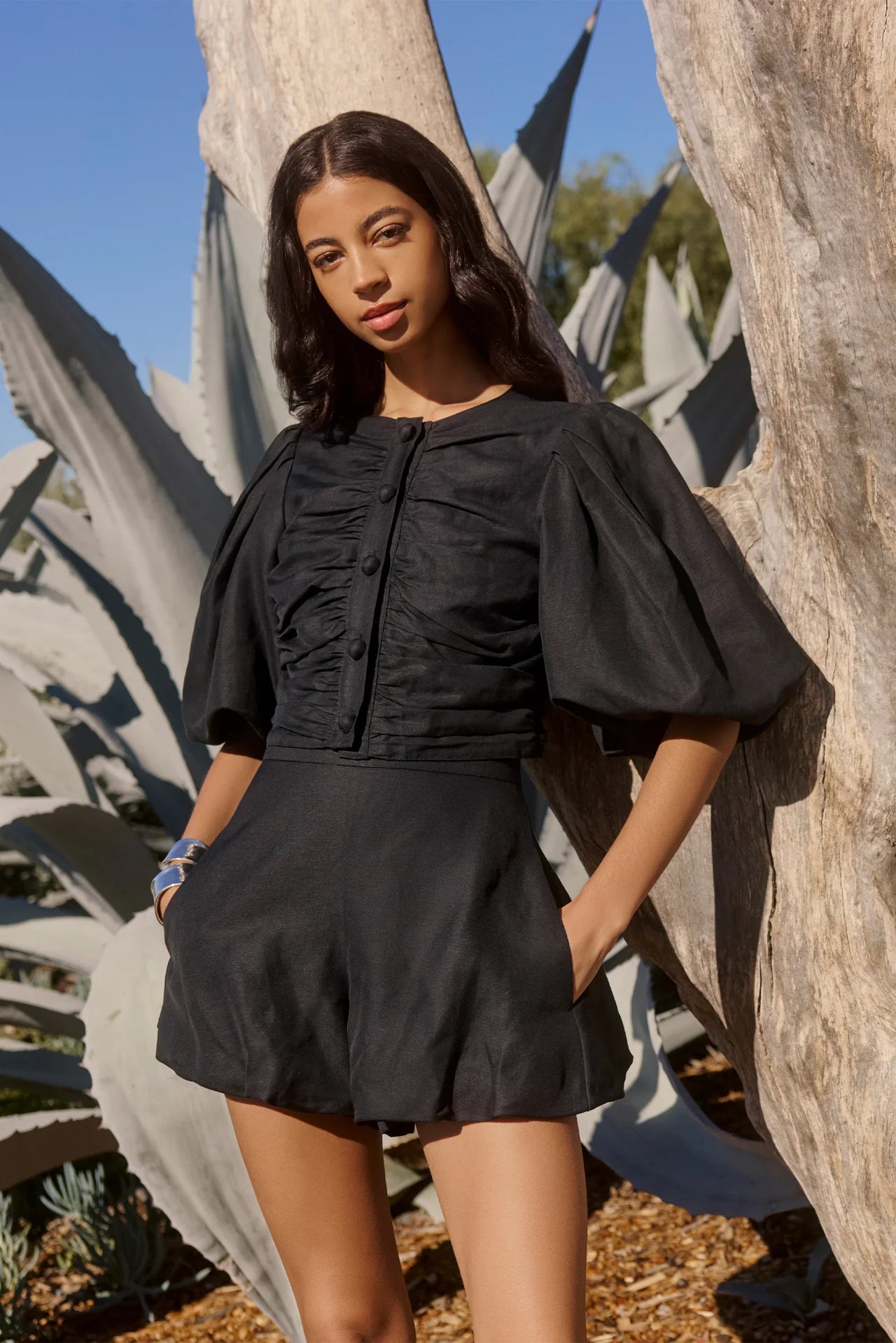 Woman in a black outfit standing against a unique architectural background