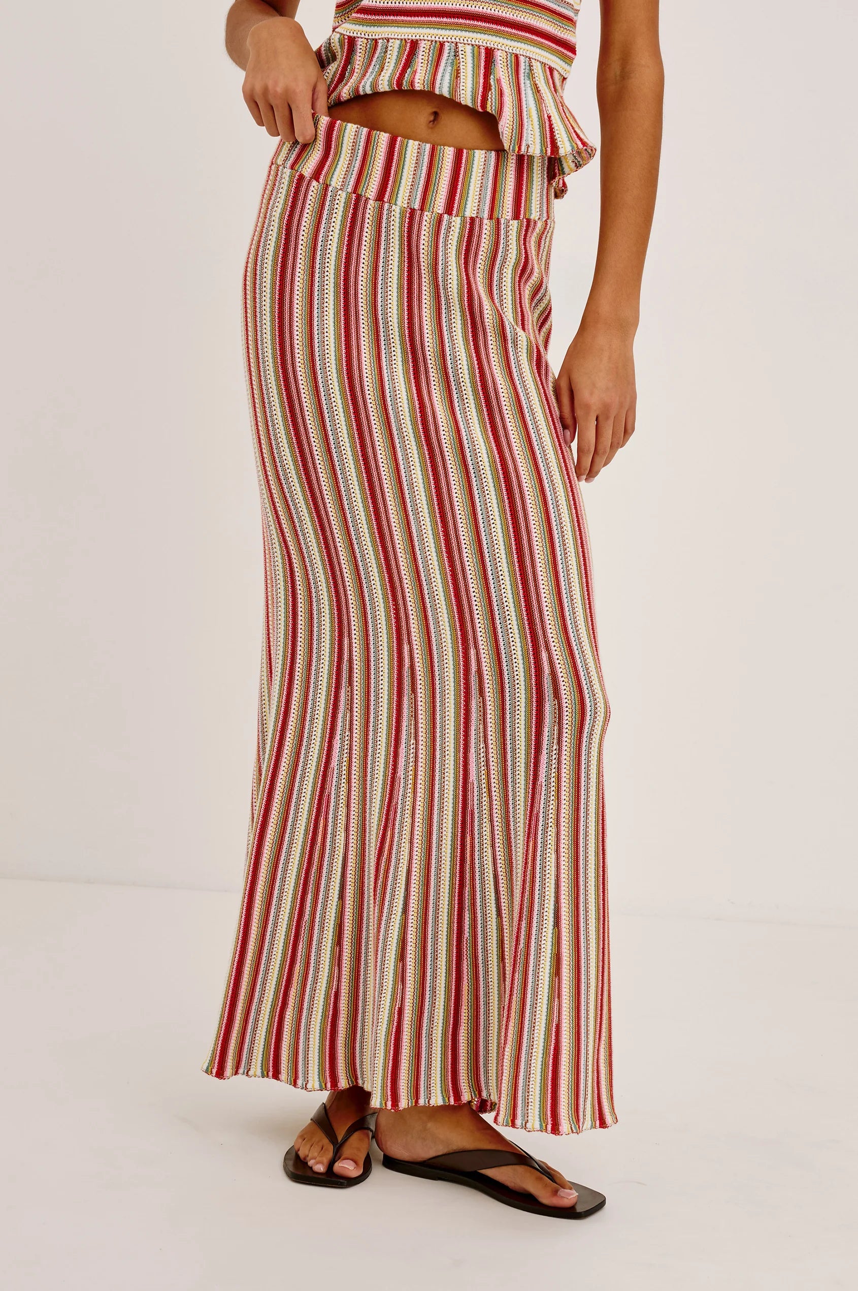 Person wearing a red and beige striped dress on a white background