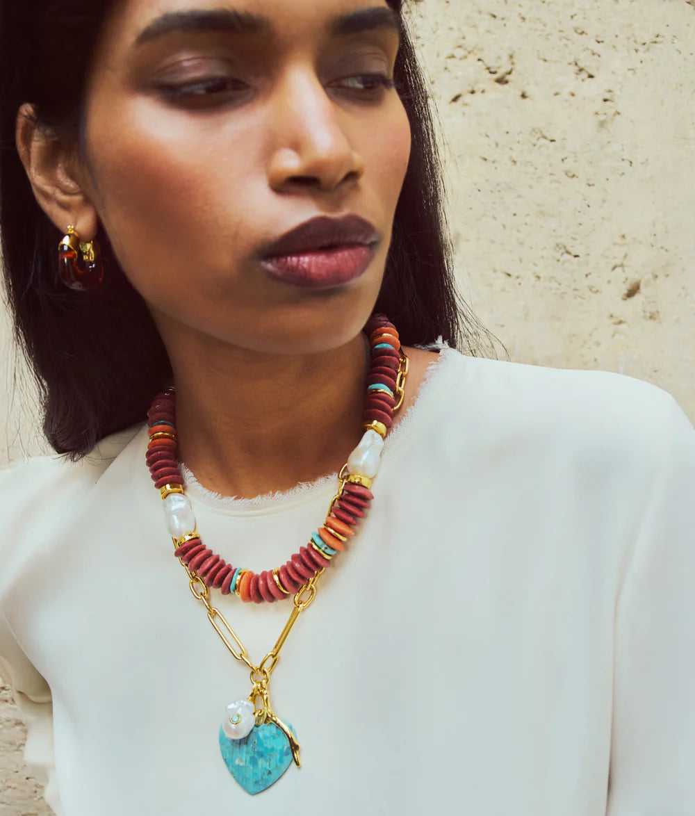 Woman wearing a colorful beaded necklace with a turquoise heart pendant.