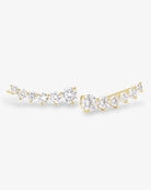 A pair of gold crescent-shaped stud earrings set with multiple round-cut clear gemstones, displayed on a clean white background.