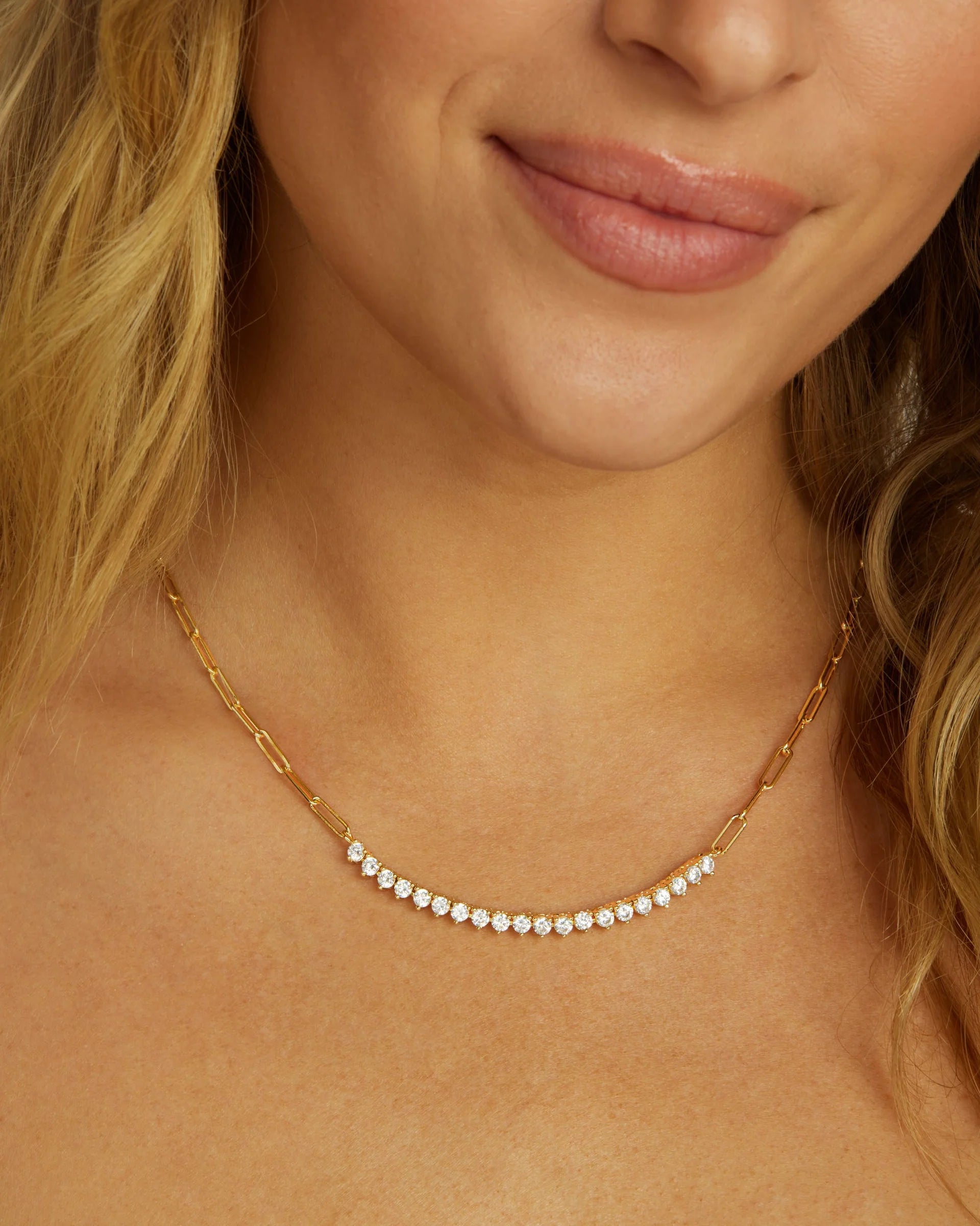 Close-up of a woman wearing a gold necklace with small pearls.