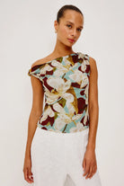 Woman wearing a floral one-shoulder top against a white background