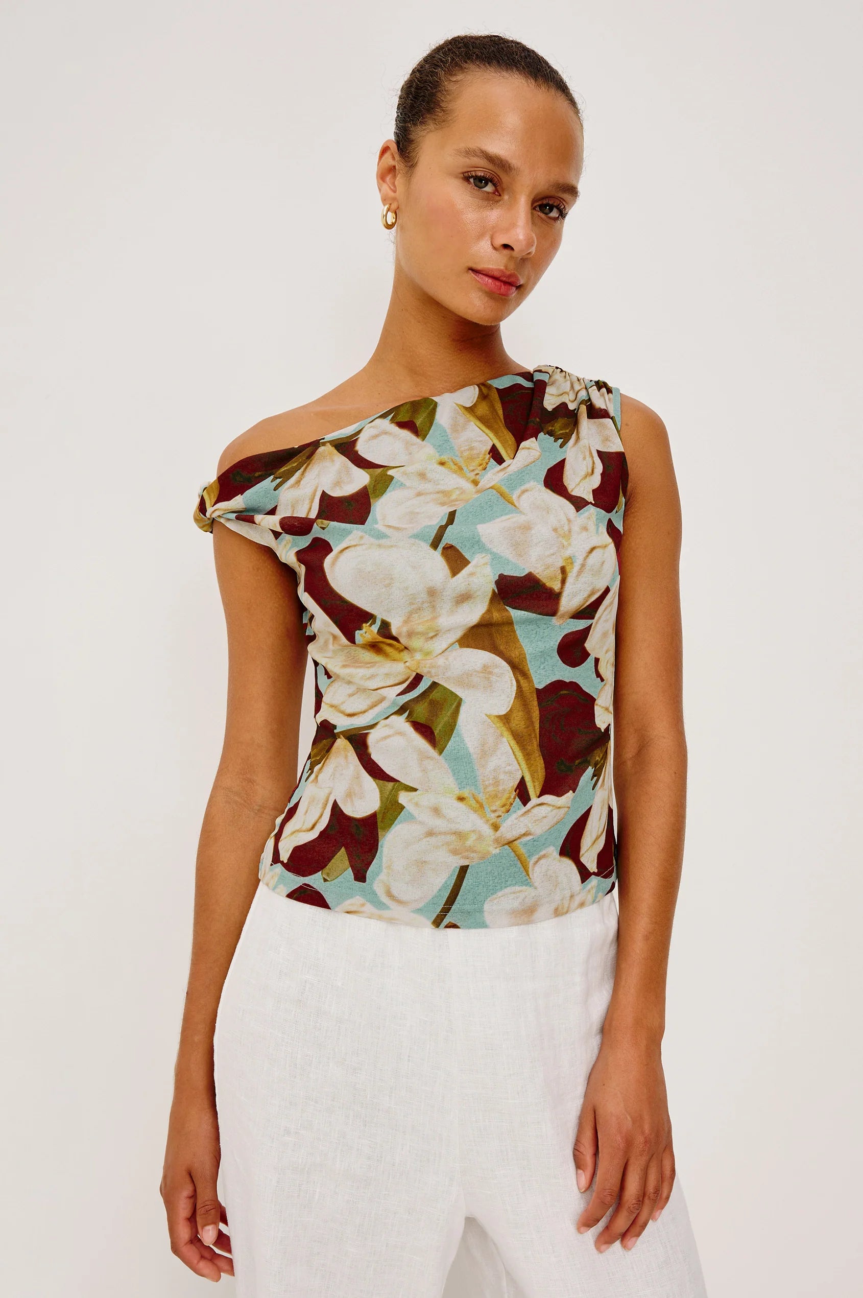 Woman wearing a floral one-shoulder top against a white background
