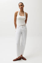 Woman wearing a white halter top and white pants on a plain background