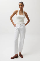 Woman wearing a white tank top and pants on a plain background