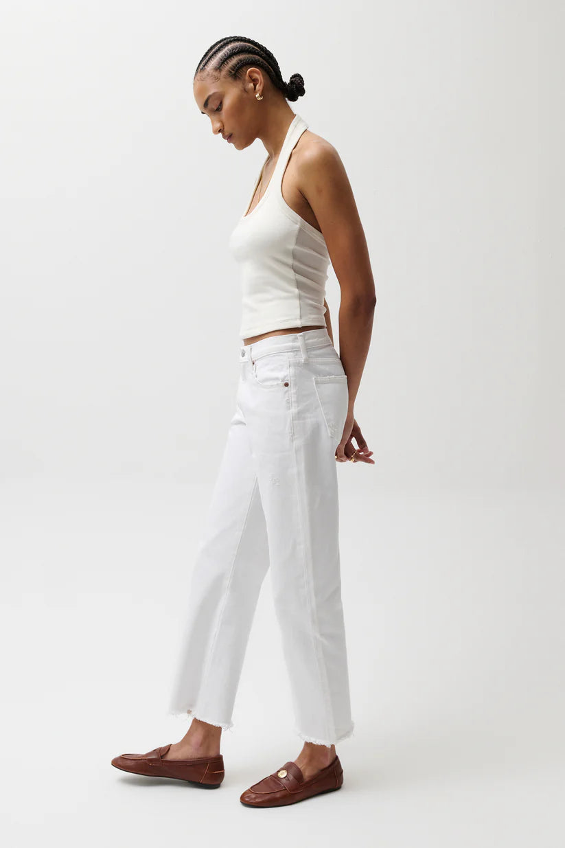 Woman wearing a white outfit with brown shoes on a light gray background