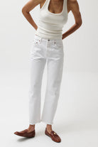 Person wearing a white tank top and white jeans on a plain background