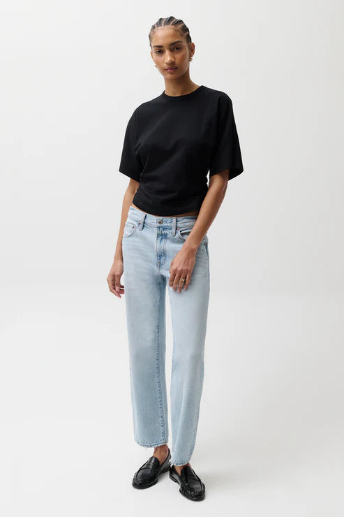 Person wearing a black t-shirt and light blue jeans on a white background