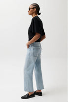 Person wearing a black t-shirt and light blue jeans on a white background