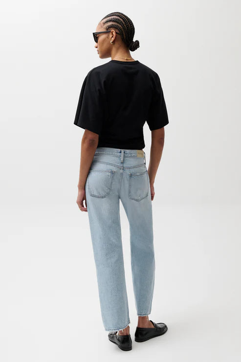 Person wearing a black t-shirt and light blue jeans on a white background