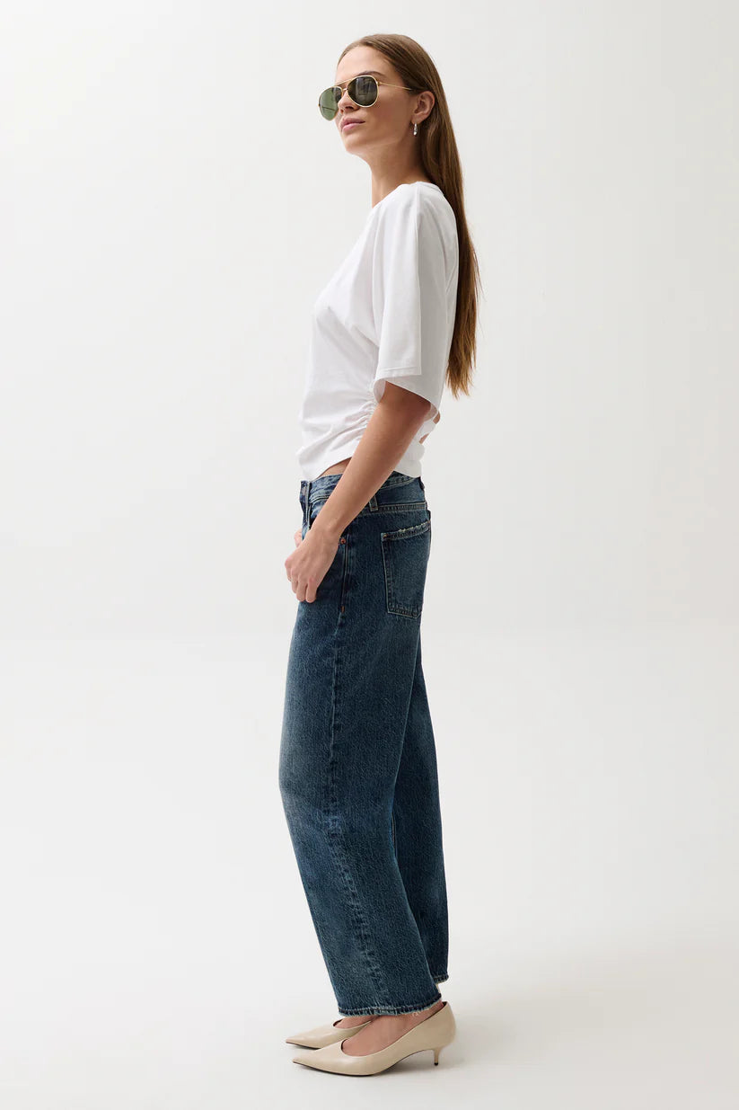 Woman wearing a white t-shirt and blue jeans on a white background