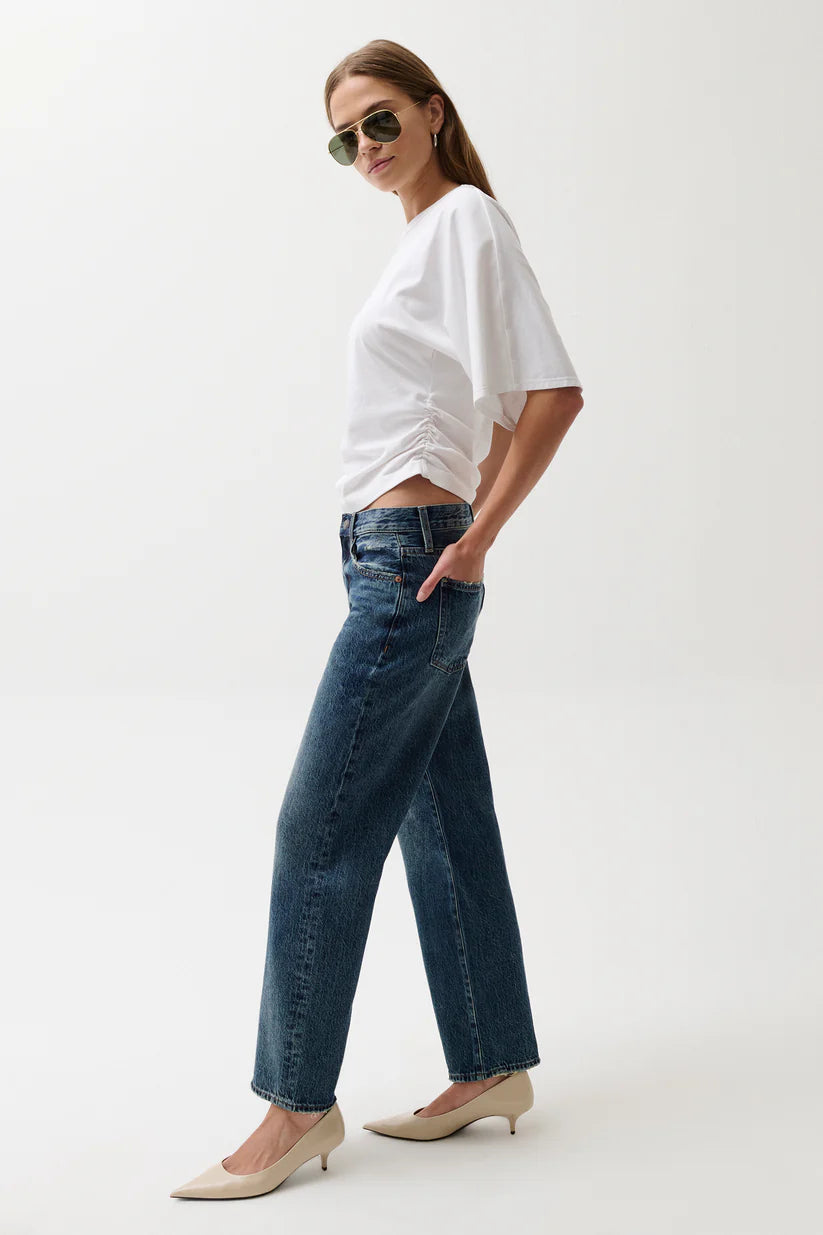 Woman wearing a white top and blue jeans on a white background