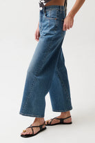 Person wearing blue wide-leg jeans on a white background