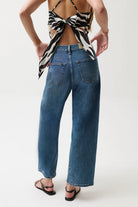 Person wearing a zebra print top and blue jeans on a white background