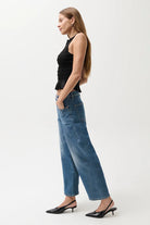 Woman wearing a black top and blue jeans on a white background