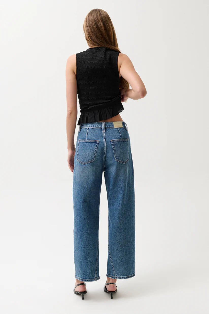 Person wearing blue jeans and a black sleeveless top on a white background