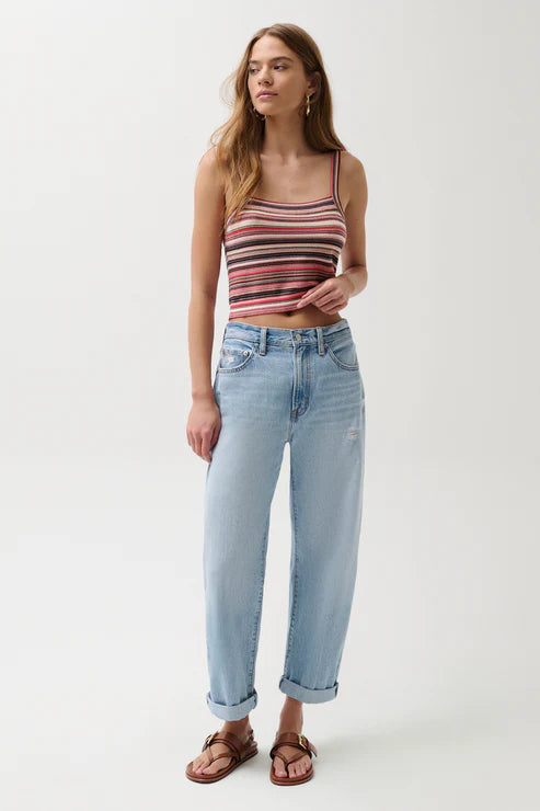 Woman wearing a striped tank top and light blue jeans on a white background