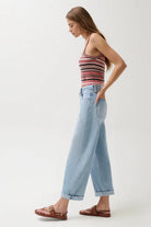 Woman wearing a striped tank top and light blue jeans on a white background