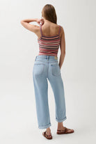 Woman wearing a striped tank top and light blue jeans on a white background