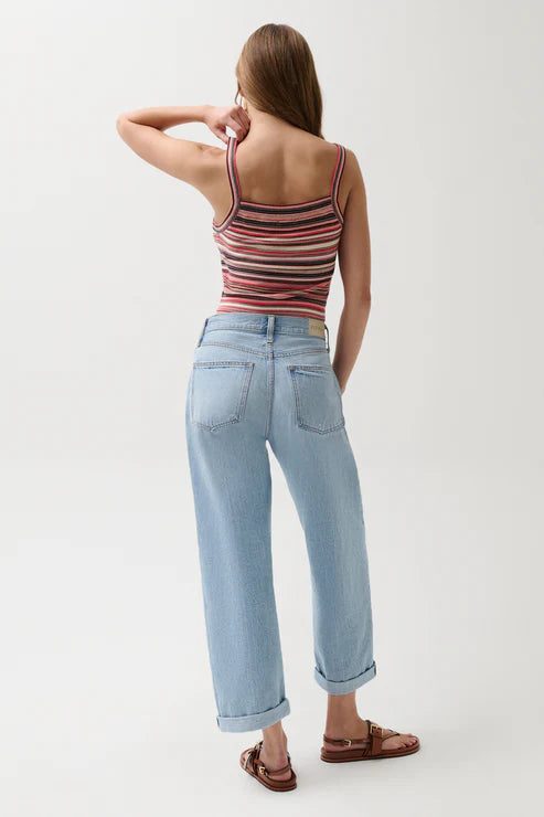 Woman wearing a striped tank top and light blue jeans on a white background