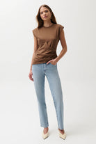 Woman wearing a brown top and light blue jeans on a white background