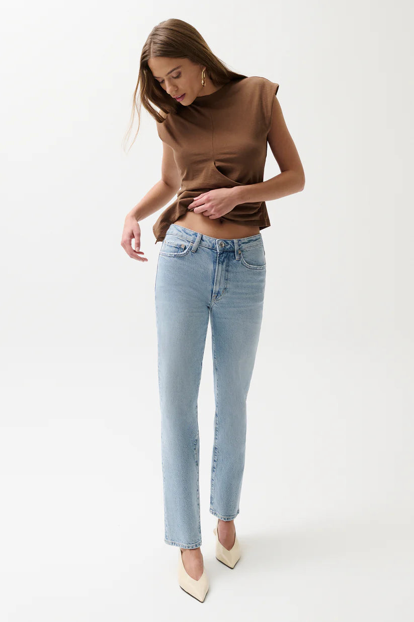 Woman wearing a brown top and light blue jeans on a white background