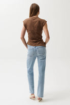 Person wearing a brown sleeveless top and light blue jeans on a white background