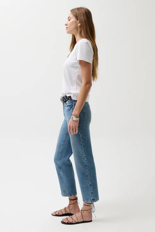 Woman wearing a white t-shirt and blue jeans standing against a white background