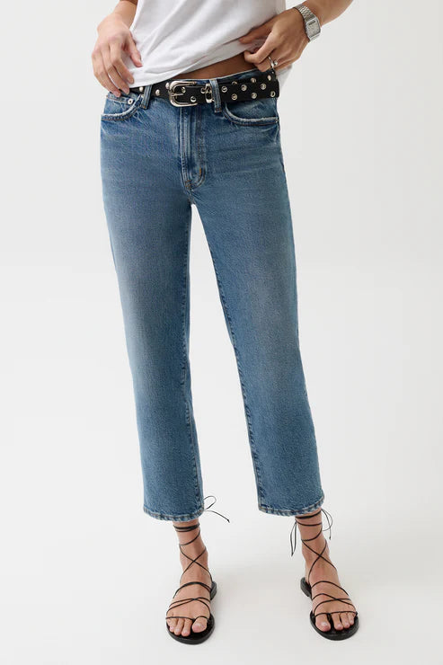 Person wearing blue jeans with a studded belt on a white background
